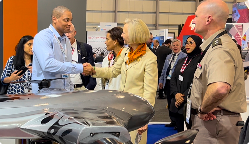 Man and woman shaking hands over an aircraft model at a trade show