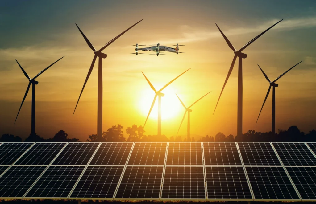 Drone inspecting solar panels and wind turbines at sunset